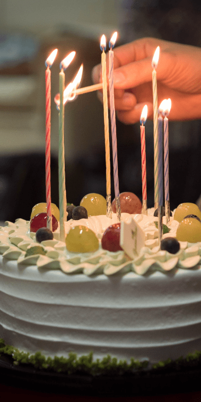 Someone lighting very thin candles on a cake.